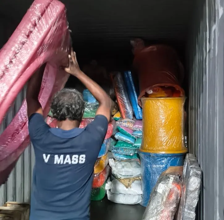 Team member lifting a wrapped bundle into a container
